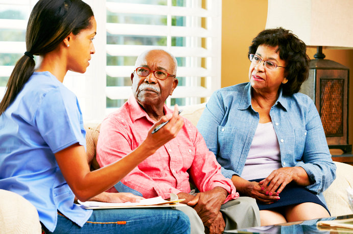 caregiver talking with senior couple wearing eyeglasses