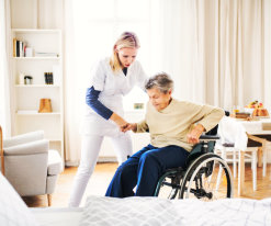 caregiver assisting senior woman to get up from the wheelchair