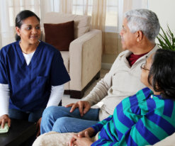 caregiver talking with senior couple sitting on the sofa