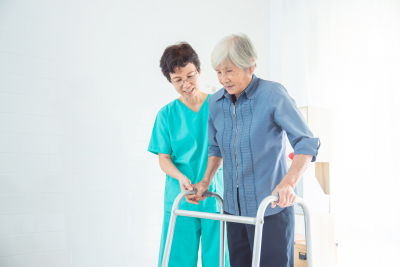 caregiver assisting senior woman walking using her walking frame