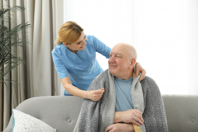 caregiver covering the senior man with blanket