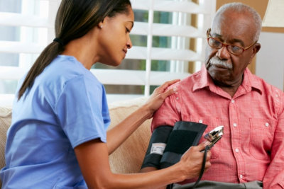 female caregiver doing blood pressure monitoring to senior man