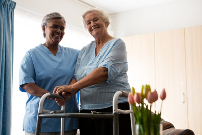 caregiver and senior woman holding her walking frame smiling