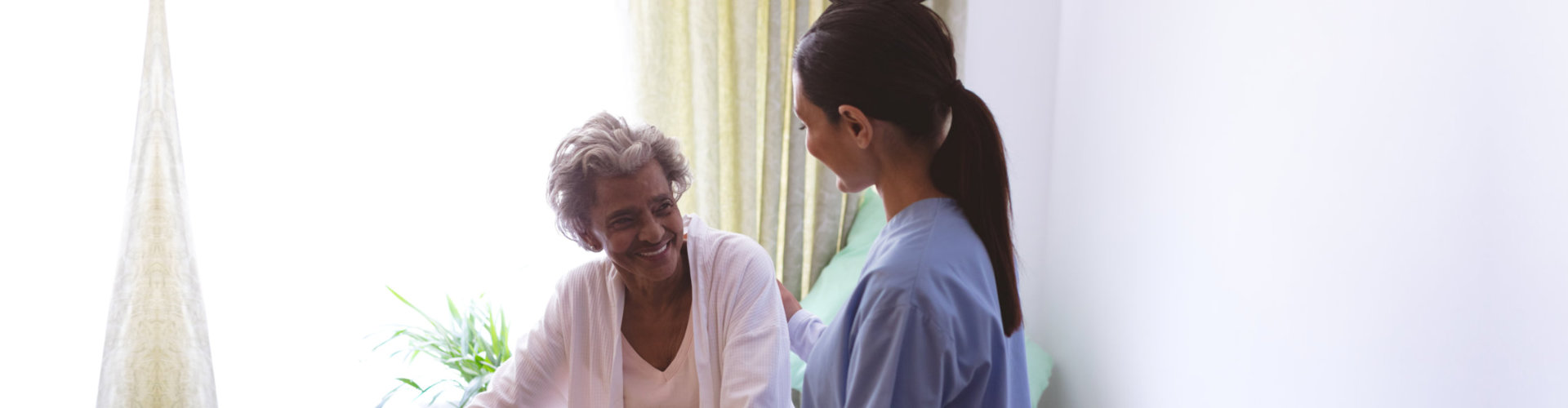 an adult woman looking at a senior woman smiling