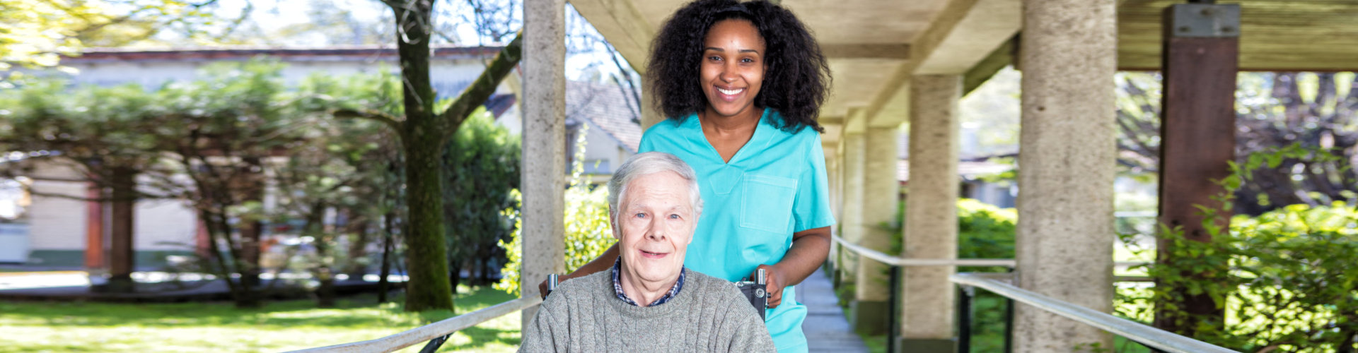 caregiver and senior woman sitting in the wheelchair smiling